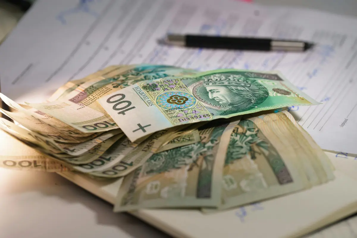 Polskie banknoty 100 zł na dokumentach – ile kosztuje upadłość konsumencka i opłata od wniosku w 2026 roku.